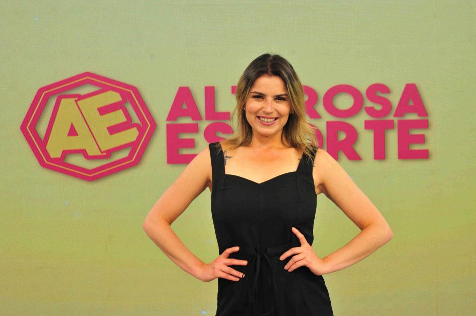 Isabel Guimarães, apresentadora, posa em frente ao telão com a marca do Alterosa Esporte ao fundo